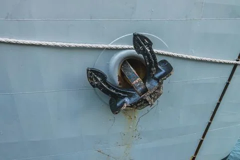 Close up of a black anchor secured on a gray ship hull 스톡 사진