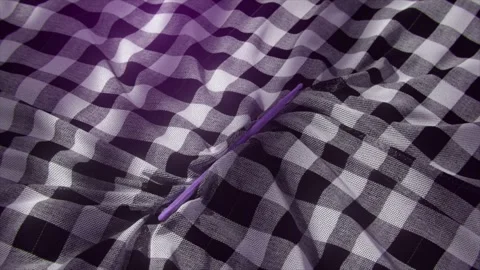 Close-up of a black and white checkered fabric with a purple stick inserted into Stock Footage 284220633