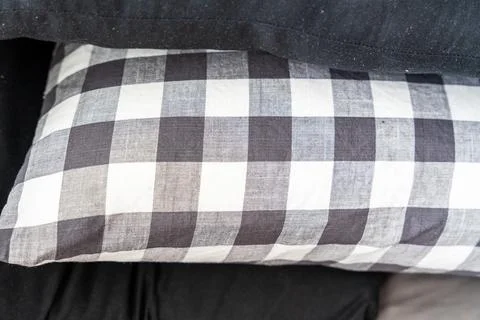 Close-up of black and white checkered pillow on top of dark fabric, adding a Stock Photos