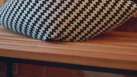 Close up of black and white houndstooth pillow resting on wooden bench with Stock Footage 344873379