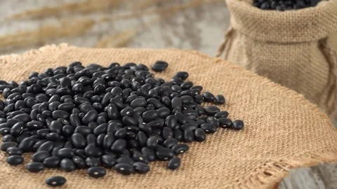 Close-up of black beans rotating on burlap. Rustic wooden background. Seamless Stock Footage 70717019