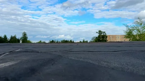 Close-up of black bitumen roofing membrane against blue cloudy sky Stock Footage 337302564