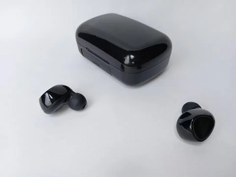 Close up of black bluetooth earbuds and closed charging case. Stock Photos