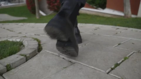 Close-Up of Black Boots Walking Along Stone Path Outdoors Vídeo Stock 335527991