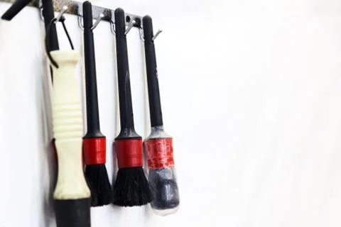 Close-up of black brushes with a red handle hanging on a white wall for indus Stock Photos