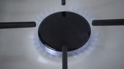 Close-up of black burner of a white enameled gas stove with a blue fire. Cast Stock Footage 162069053