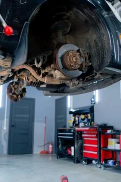 Close-up of a black car without wheels raised at a service station by special Stock Photos