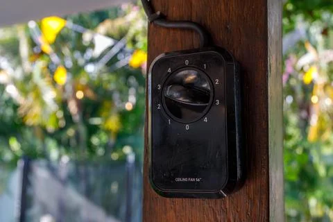 Close-up of a black ceiling fan speed control switch mounted on a wooden post Stock Photos