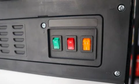 Close-up of a black control panel with green, red, and orange rocker switch.. Stock Photos