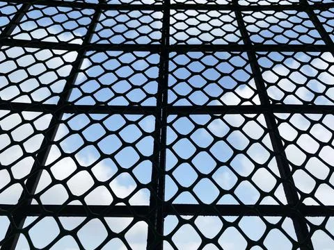 Close Up of Black Diamond Mesh Pattern Against Blue Sky and Cloud Background 스톡 사진
