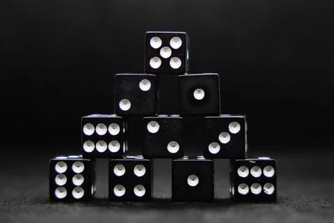 Close up of black dice stacked in the shape of a pyramid isolated on a black bac 스톡 사진
