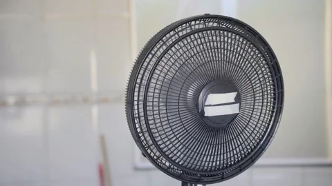 Close up of a black electric table fan standing in a bright minimalist room Stock Footage 346644032