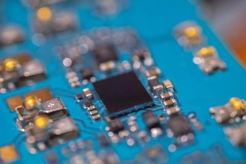 Close up of black electronic chip on blue circuit board with tiny component.. Stock Photos