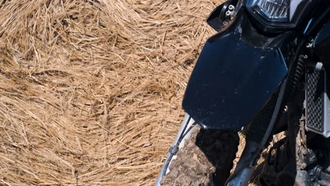 Close up of a black enduro motorcycle in front of a yellow haystack 스톡 동영상 220150657