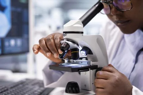 Close up of black expert analyzing samples in chemistry lab with microscope 스톡 사진