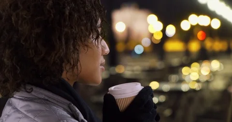 Close up of black female drinking coffee at outdoor cafe in Paris at night Stock Footage 82629227