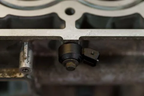 Close-up of a black knock sensor installed on engine block. Foto stock
