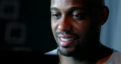 Close-up black man face looking at computer screen at night Stock Footage 145321031
