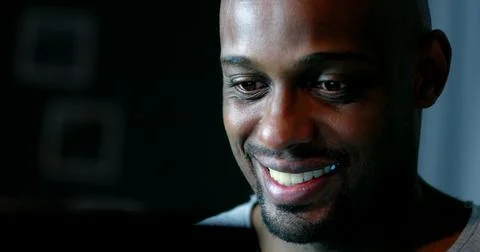Close-up black man face looking at computer screen at night Stock Photos