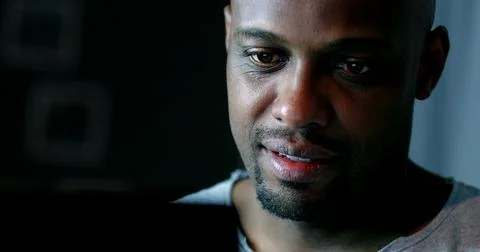 Close-up black man face looking at computer screen at night Foto stock