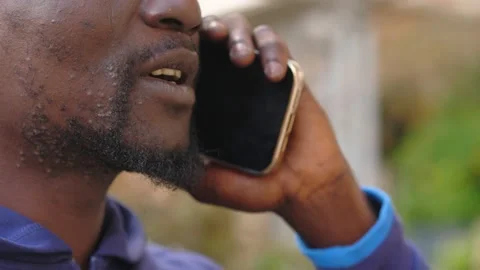 Close up of a black man focused in a mobile phone conversation in the street Stock Footage 218602754