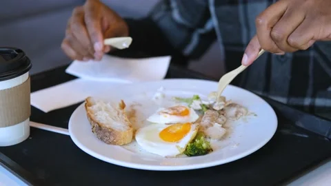 Close-up of a black man having breakfast with scrambled eggs in a cafe Stock Footage 234548871