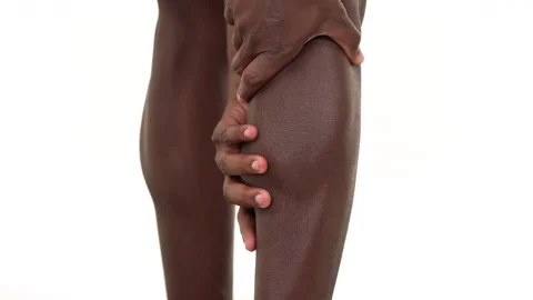 Close up of a black man massaging his leg. Isolated on a white background. Stock Footage 161958416