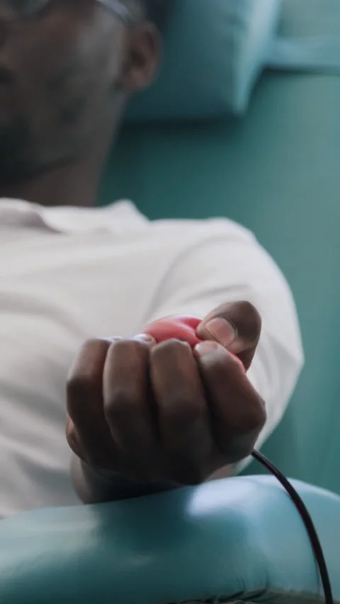 Close-up of Black Man Squeezing Stress Ball to Aid Blood Flow During Donation Stock Footage 317050328