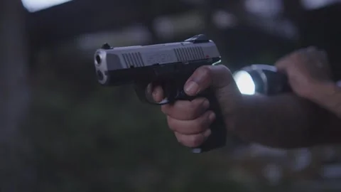 Close up of a black mans hand holding a handgun and flashlight as he scans Stock Footage 255565541