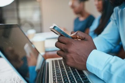 Close up of Black man's hands using phone during meeting, with laptop Stock Photos