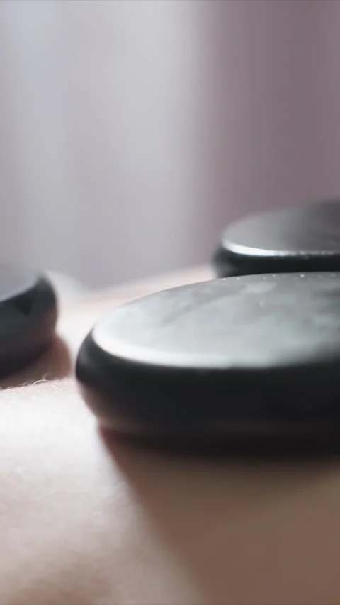 Close up of Black Massage Stones on Human Skin Detail showing relaxation therapy Stock Footage 346796594