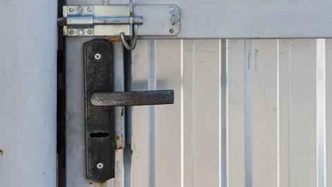 Close-up of a black metal handle and a silver sliding latch bolt installed on Fotos de archivo