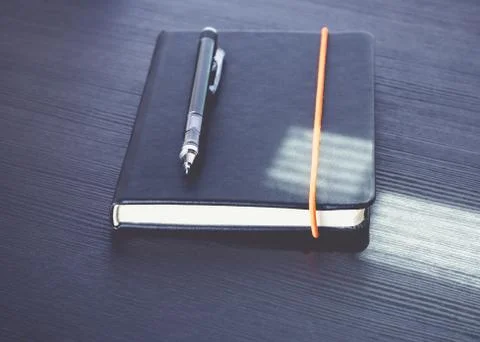 Close up black notebook with modern mechanical pencil on black wood table wit Stock Photos