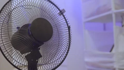 Close-up of a black oscillating fan in a softly lit room Stock Footage 314963100