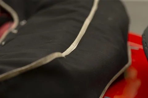 Close-up of black padded jacket sleeve with white piping on red background Foto stock