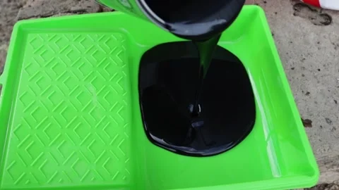 Close-up of black paint pooled in a green roller tray outdoors, showing coa.. Stock Footage 345412225
