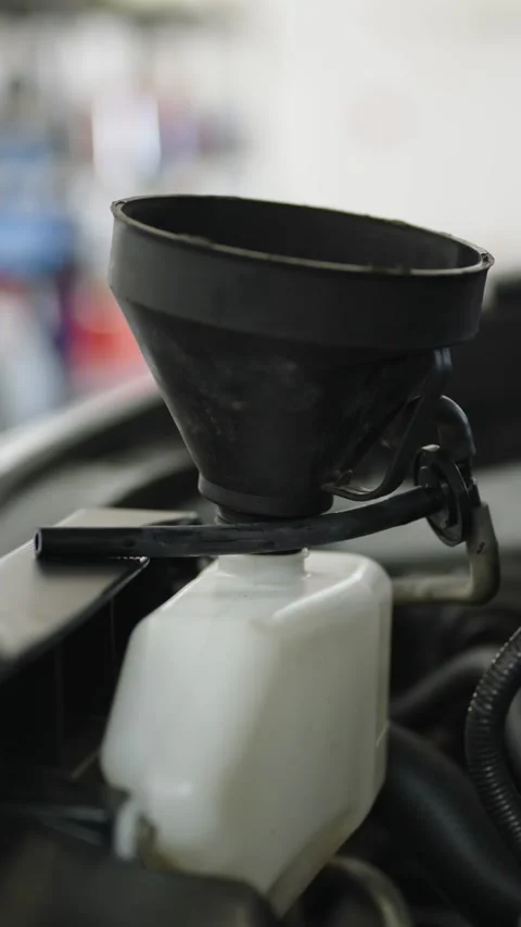 A close-up of a black plastic funnel inserted into the neck of a white Stock Footage 336710328