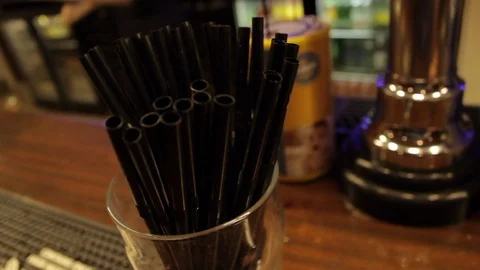 Close up of black plastic straws on top of a bar Stock Footage 107628200