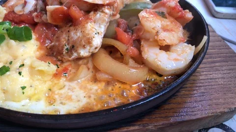 Close up of black roaster with cooking chicken, potato, tomato, and cheese. Stock Footage 104200117