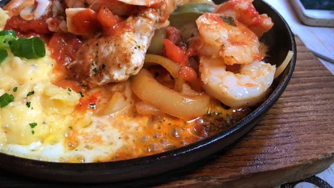 Close up of black roaster with cooking chicken, potato, tomato, and cheese. Stock Footage 104203870