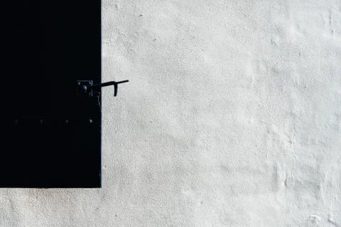 Close up of a black shutter on a white plaster covered wall in old house in.. Stock Photos