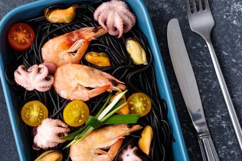 Close up black spaghetti with ink cuttlefish with seafood in blue plate with Stock Photos