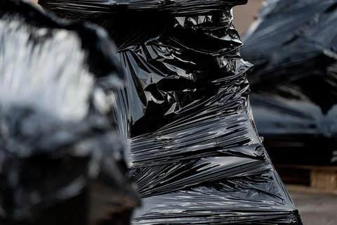 Close-up of black stretch-wrapped pallets on outdoor surface Stock Photos