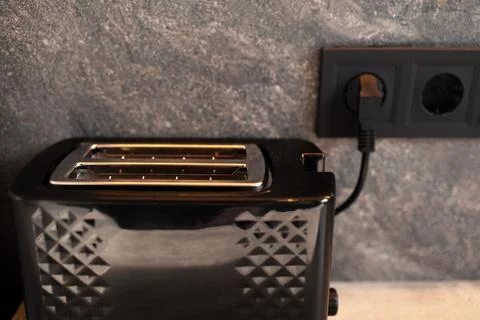 Close-up of black toaster connected to socket. Stock Photos