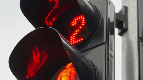 A close-up of a black traffic light counts down the time for pedestrians with a Stock Footage 218948944