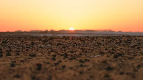 Close Up of Black Volcanic Rocks on Desert Sand and Rack Focus to Sunset in the Stock Footage 341994805