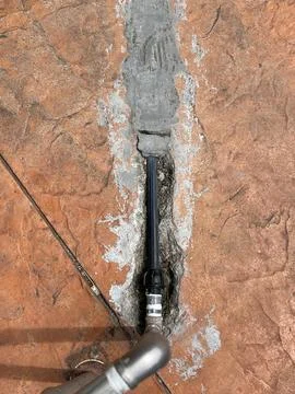 Close-up Black Water Pipe Embedded in Concrete Floor During Repair Foto stock