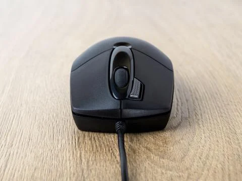 Close-up of black wired optical mouse over brown desk. Stock Photos