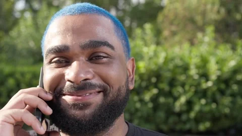 Close-up of black young man talking to a friend with mobile phone 스톡 동영상 285659084