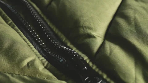Close-up of a black zipper on an olive green puffer jacket.  Stock Footage 346188393